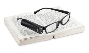 OrCam MyReader 2 an Brille montiert, auf einem Buch liegend